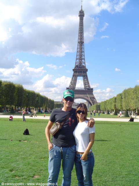 Couple posing on the lawn in front of the Eiffel Tower, Paris, cloudy sky