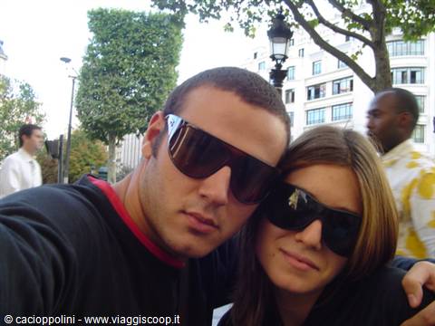Couple wearing dark sunglasses taking a selfie on a tree-lined city street