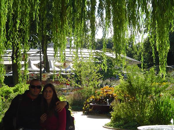 Couple under willow branches in a blooming garden with glasshouse