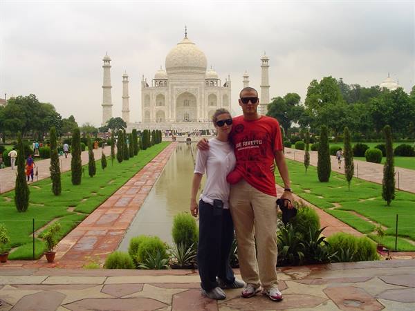 Couple posing in front of the Taj Mahal, central canal and gardens