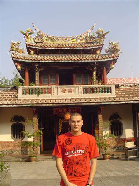 Tourist in red shirt before a Chinese temple with decorated roof