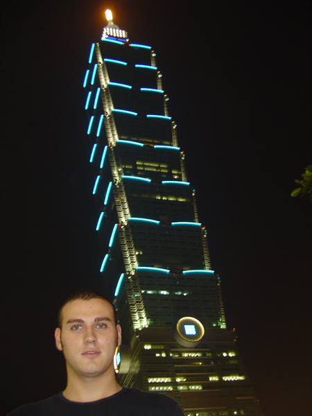 Young man in front of Taipei 101 lit in blue at night