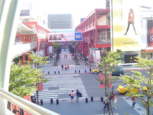Pedestrians cross the street at Ximending, red buildings and yellow taxis