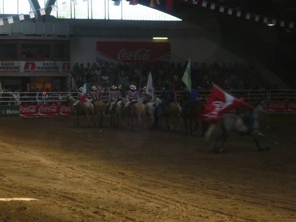 Riders with flags parade on horseback in the indoor arena before the crowd