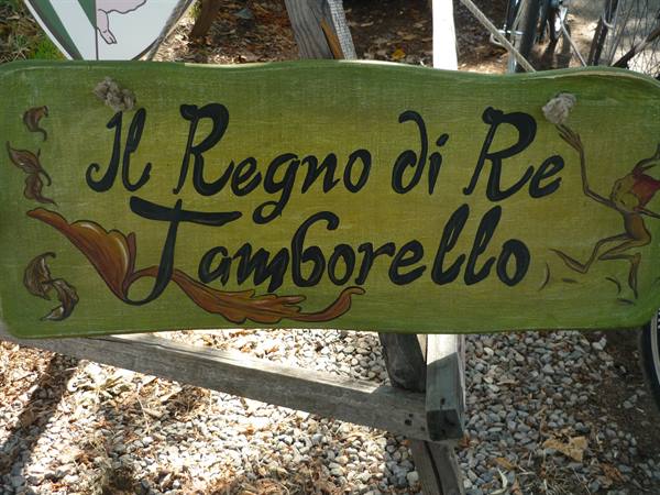 Hand-painted green wooden sign reading Il Regno di Re Tamborello, natural daylight