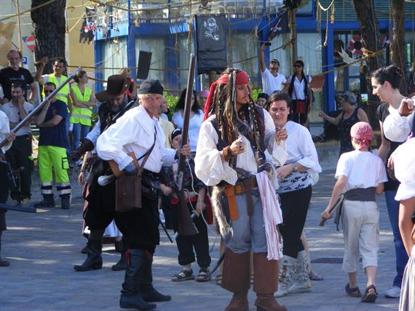 Men in pirate costumes with rifles parading through a town square