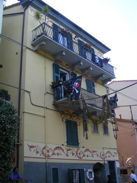 Yellow house with flowered balconies, pirate flags and fishing nets hanging