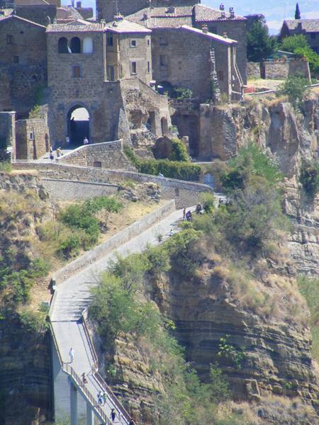 Footbridge over tuff cliff leading to Civita di Bagnoregio, tourists walking up
