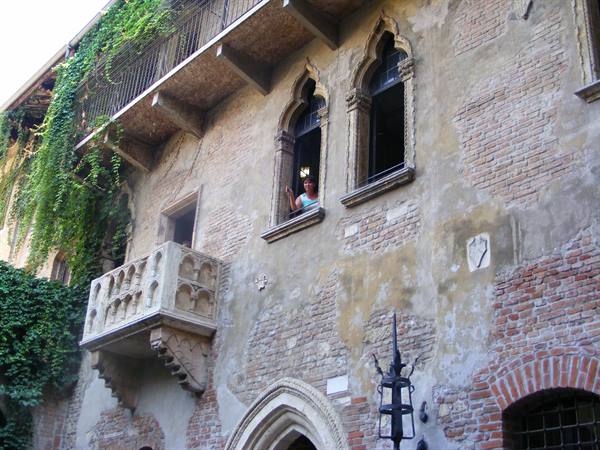 Woman waving from the brick Gothic palace window with marble balcony in Verona