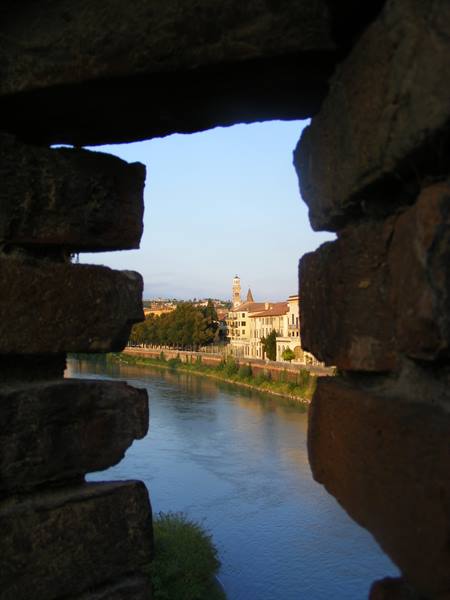 The Adige river and Verona's buildings seen through a brick wall gap