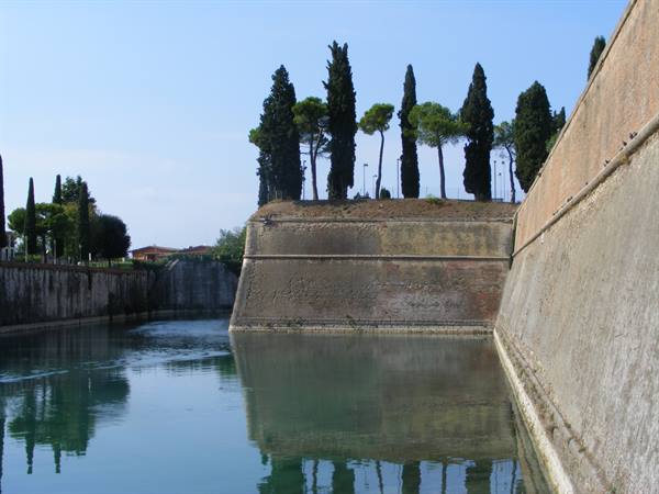 Brick bastion with cypress trees reflected in the moat water