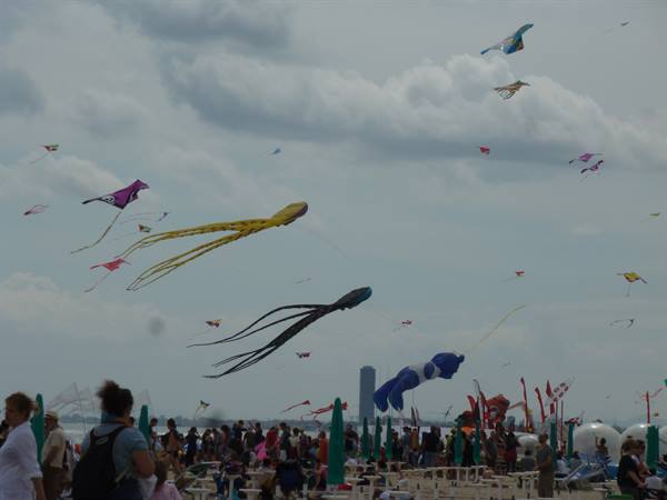 Octopus-shaped kites flying above a crowded beach with green umbrellas