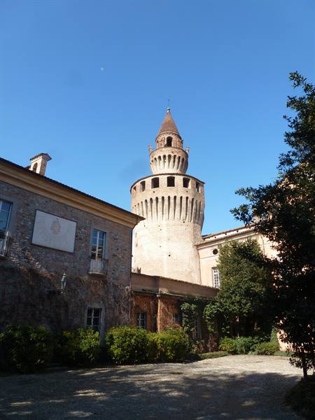 Brick tower with Ghibelline merlons rising above a castle courtyard