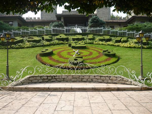 Floral clock spelling Rosée in a garden before the castle