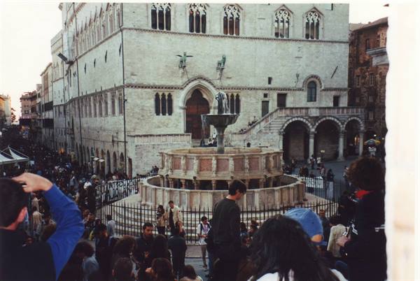 Crowd around Perugia's Fontana Maggiore, Palazzo dei Priori stone facade behind