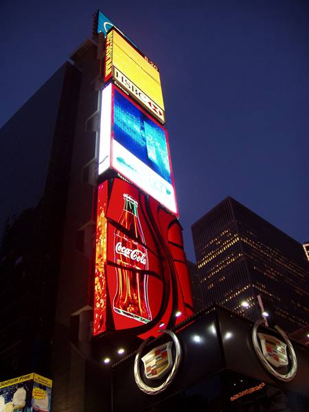 Times Square, New York: skyscraper with glowing Coca-Cola and Cadillac billboards