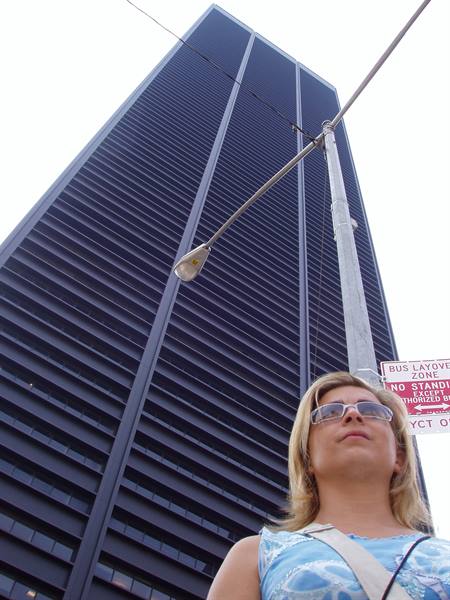 Blonde woman in sunglasses in front of a dark skyscraper, streetlight