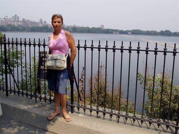 Woman leaning on the iron fence at the Jacqueline Kennedy Reservoir, Central Park