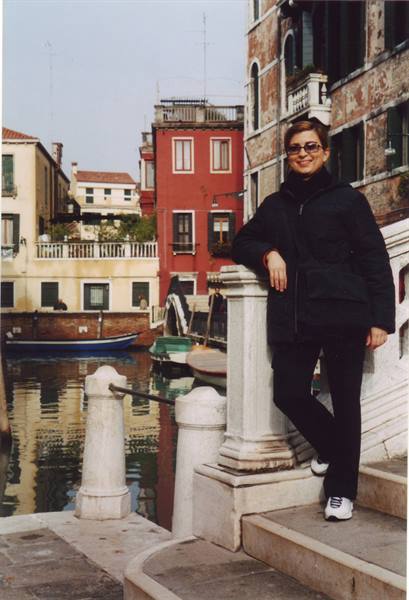 Smiling woman leaning on a marble post beside a canal in Venice