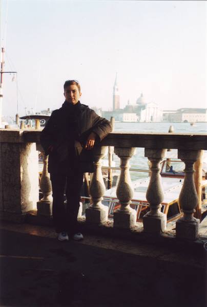 Man leaning on stone balustrade in Venice, San Giorgio Maggiore in the background