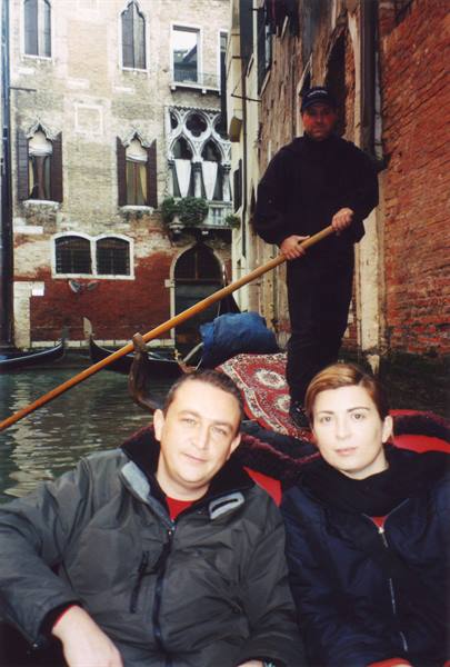 Couple on a gondola with gondolier, Venice canal among old buildings