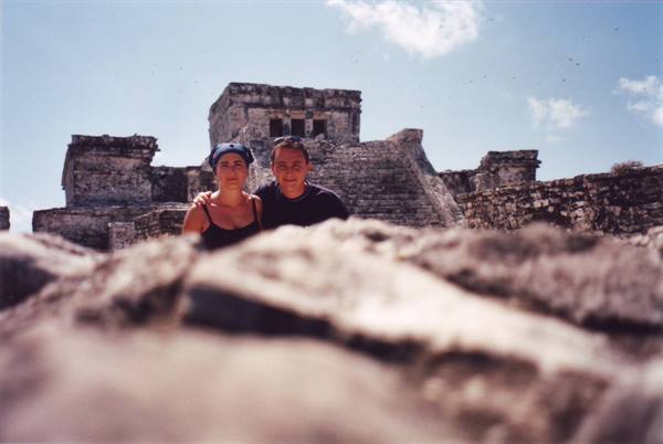 Couple in front of Mayan stone ruins at Tulum, blue sky
