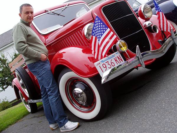 Man beside a red 1936 Ford pickup with American flags, Massachusetts