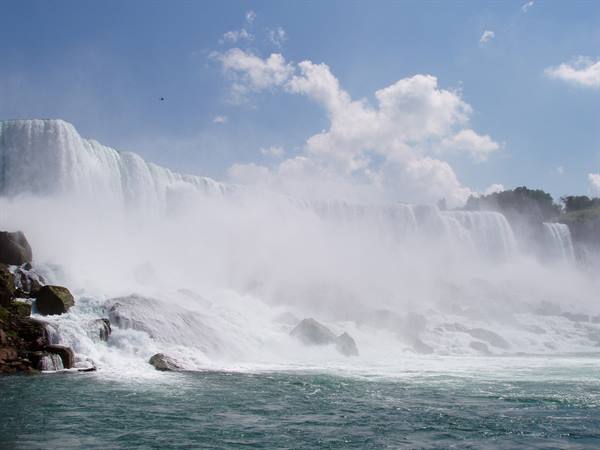 Niagara Falls: rushing water cascading into mist over wet rocks