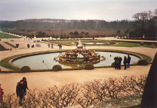 Visitors around the Latona fountain in the gardens of Versailles, grey sky