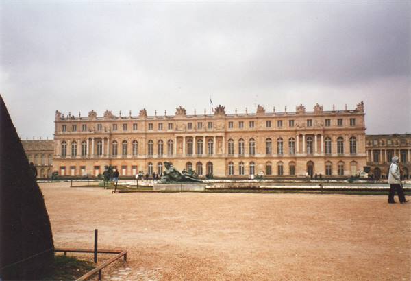 Light stone facade of the Palace of Versailles, gravel courtyard, grey sky