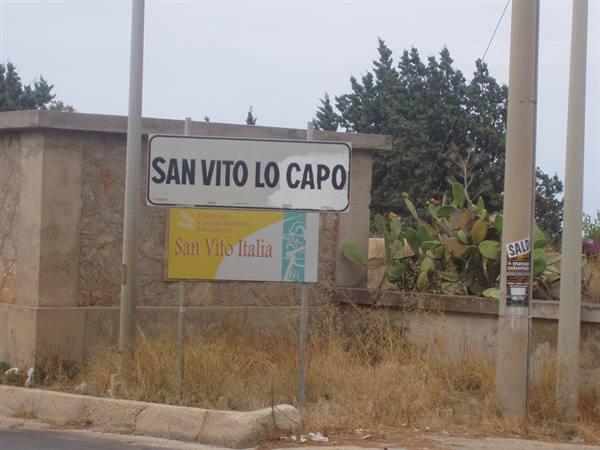Road sign of San Vito Lo Capo among prickly pears and dry grass