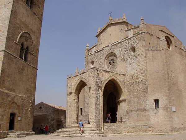 Erice cathedral in stone with rose window and bell tower, tourists on steps