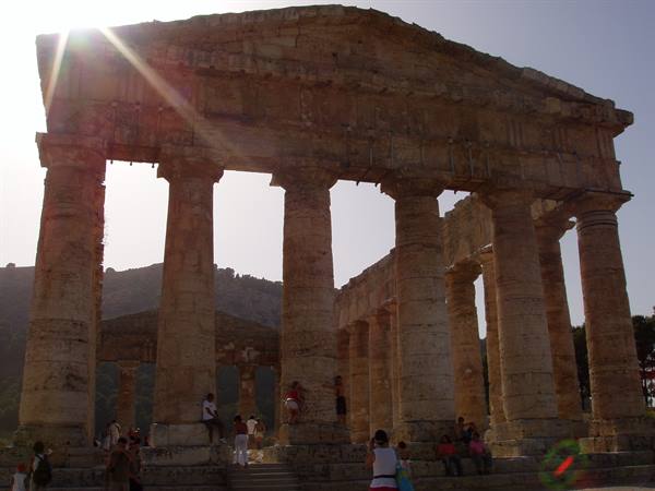 Tourists beneath Doric columns of Segesta temple, bright sunlight