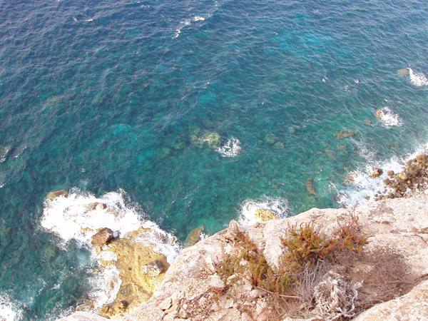 Limestone cliff above turquoise sea, white foam breaking over rocks