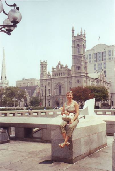 Woman sitting on a marble block in front of a gray stone church