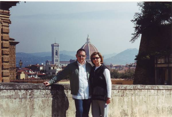 Couple by a stone wall with Florence Cathedral dome in the background