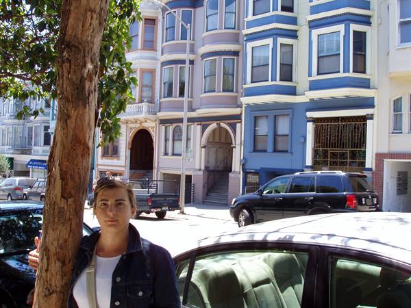 Girl beside a tree in front of blue Victorian houses in San Francisco