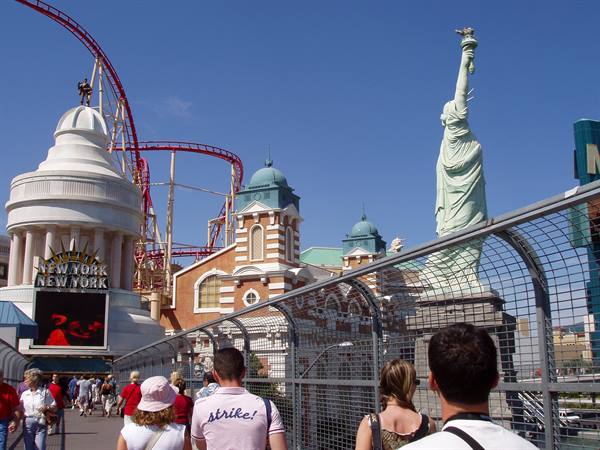 Tourists on the walkway in front of New York-New York hotel with roller coaster and Statue of Liberty