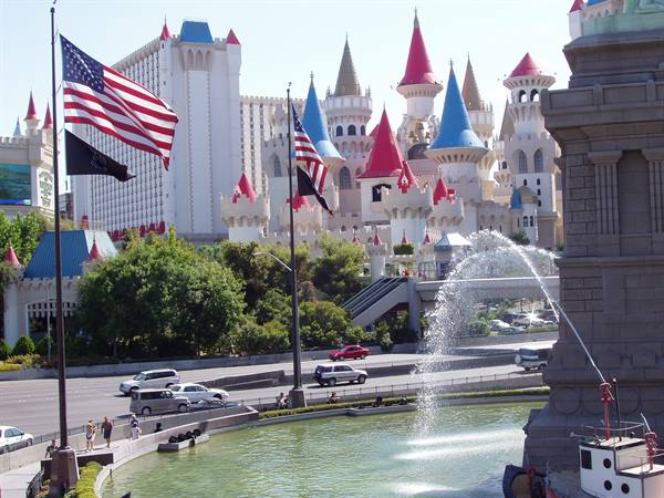 American flags and fountain in front of Excalibur hotel's pink and blue towers