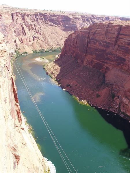 The green Colorado River flows between red Glen Canyon cliffs