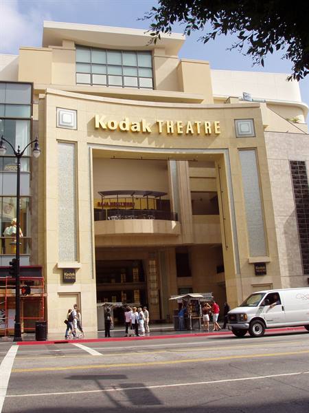 Tourists at the Kodak Theatre entrance, beige facade, white van on the street