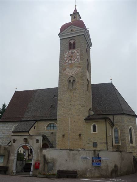 Stone church with tall clock tower under a grey sky