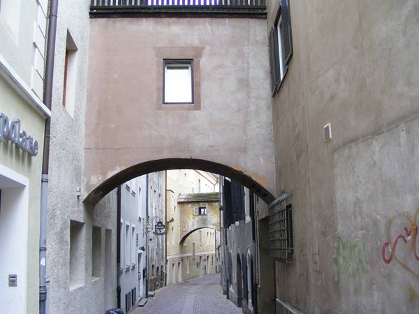 Masonry arch over a cobbled alley between old ochre building facades