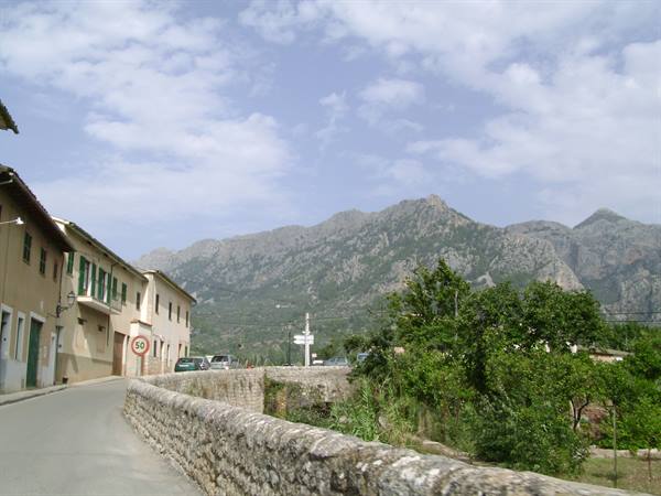 Stone road between ochre houses and rocky mountains under clouds