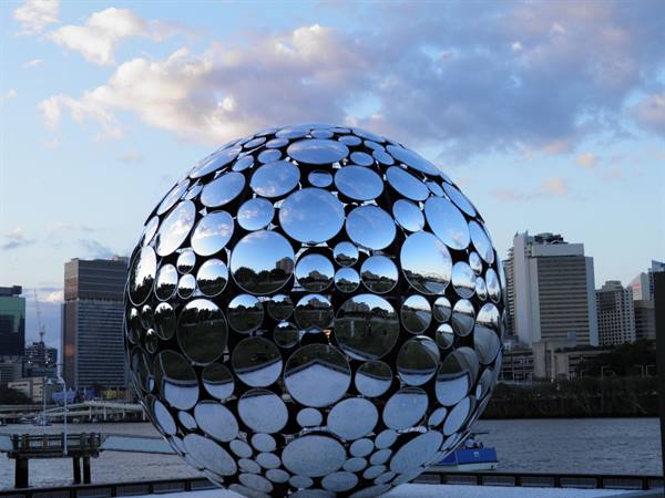 Mirrored steel sphere sculpture by the river, Brisbane skyscrapers behind