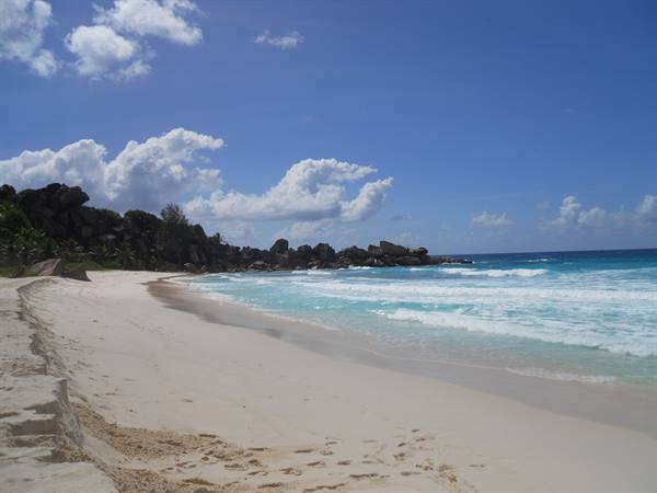 White sand beach with turquoise waves and granite boulders at La Digue