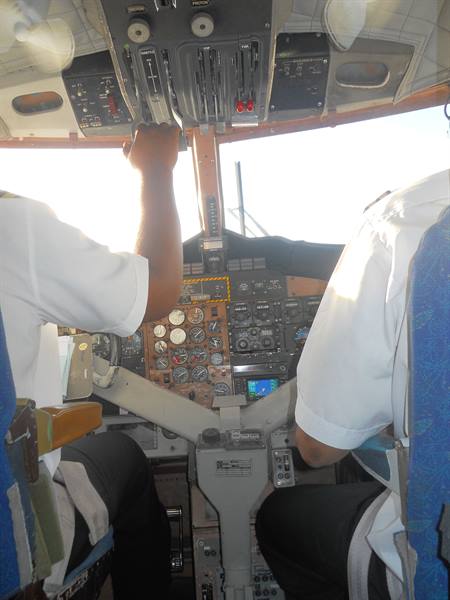 Two pilots in white shirts in the cockpit, analog gauges and throttle levers