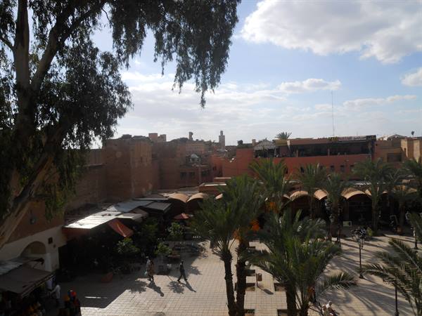 Jemaa el-Fna square in Marrakech, palm trees and red brick arcades