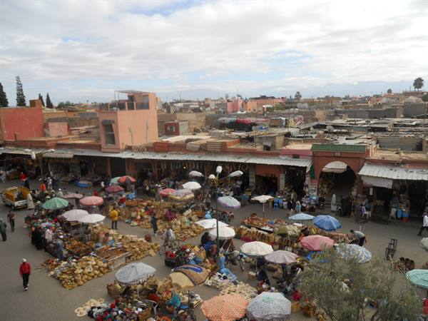 Open-air market with colorful parasols among Marrakech red walls