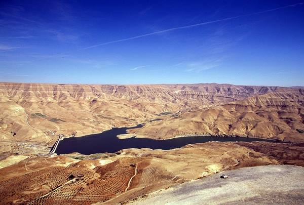 Wadi al-Mujib dam lake between arid desert hills under blue sky